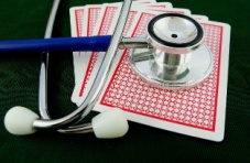 A close-up photo of a deck of cards with a stethoscope on, on a dark surface