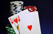 An image of a King and Ace of Hearts placed against stacks of casino chips on a dark blue background