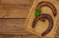An image of two horseshoes and a clover, both symbols of good luck, on a wooden table