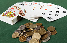 A photograph of a deck of cards with a few cards spread out face-up and pile of coins on a green felt table