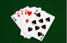 Cards showing three Aces and two eights on a poker table