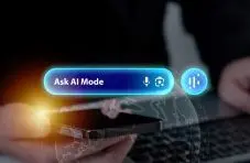 A photograph of hands holding a phone with a glowing "Ask AI Mode" search bar hologram on a dark background