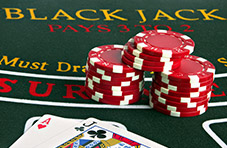 casino chips and A-J cards sitting on a standard green blackjack table