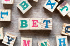 A photo of the word ‘Bet’ in different coloured alphabet blocks with random letters scattered around