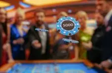 A photograph of blue 5000 casino chips flying in the air with blurred people at a roulette table background