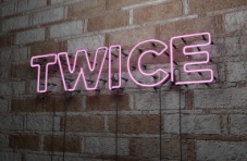 A pink neon twice sign on a stone wall