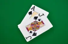 An illustration of an ace and a jack of spades, isolated on a green background.