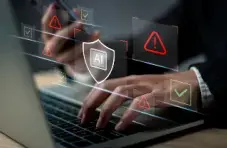 An illustration of hands typing on a laptop with AI security icons and warning symbols on a dark technology background