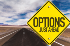 A desert road with a yellow traffic sign displaying ‘options just ahead’