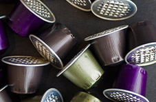 A photo of colourful used coffee pods on a dark grey background