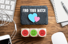 A piece of slate with the words ‘find your match’ surrounded by office supplies on a wooden surface 