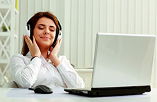 woman enjoying listening to music with headphones with her laptop Springbok games on the table. 