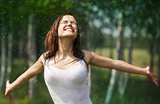 A photo of a woman thoroughly enjoying herself outdoors in the woods in nature