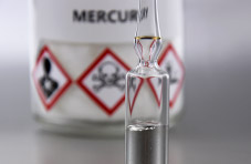 An image of a glass ampule containing mercury with a white container in the background labeled mercury, showing toxic warnings 