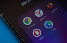 A photograph of a mobile screen showing browser app icons including Chrome, Firefox, Edge, Opera and Yandex on a dark background