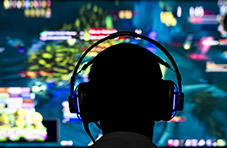 silhouette of a gamer sitting in front of a gaming screen with headphones on.