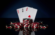 Three aces of different suits with stacks of poker chips against a dark background