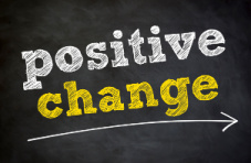 A blackboard with the words ‘positive change’ written in white and yellow chalk