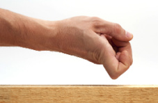 A photo of a male hand knocking on wood against a white background
