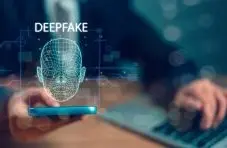 Photo of hands holding a smartphone with a glowing 3D wireframe face hologram and "DEEPFAKE" text on a dark blue background