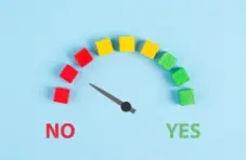An illustration of a gauge made of coloured blocks pointing from no to yes on a light blue background
