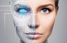 An image of a female robot with half her face showing a robotic interface and the other half looking human on a grey background