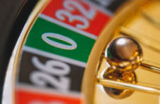 A close-up photo of a roulette wheel with the ball on the green zero pocket