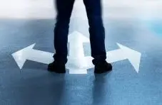 A photograph of a person's legs standing over three direction arrows on a grey asphalt background