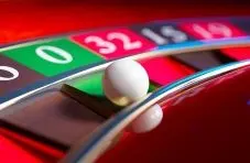 A photograph of a white ball on a casino roulette wheel showing numbers on a red and green background