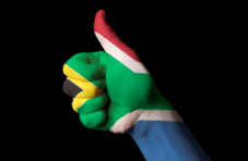A photo of a human hand painted with the South African flag giving a thumbs up, isolated on black