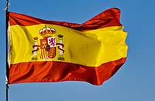 A photo of a raised Spanish flag against a clear blue sky