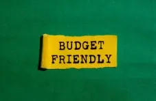 An image of a torn yellow piece of paper with the words “budget friendly” printed in black, on a green background