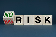 An image of wooden blocks displaying ‘no risk’ and ‘big risk’ on a dark background