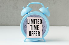 A photo of a 'limited time offer' message stuck on a light blue desk clock on a white surface against a grey wall