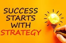 A photograph of a hand writing "Success Starts With Strategy" beside a crumpled paper lightbulb on an orange background