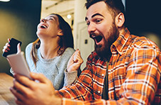 Two friends winning playing slots and video poker on their phones