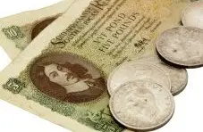 A close-up photo of an old South African five pound banknote with silver coins on white background