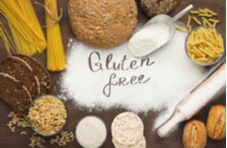 An assortment of breads, pasta and grains surrounding the words ‘gluten free’ traced in white flour
