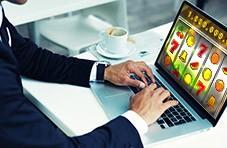 a man in a business suit, playing casino games on his laptop