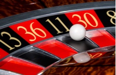 A close-up photograph of a segment of the roulette wheel with a white ball in the number 11 pocket 