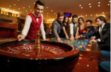 croupier throwing the ball into a roulette wheel with the players behind