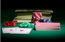 An image of a huge stack of dollar bills and out-sized playing cards and casino chips