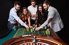 a roulette wheel with people standing around betting