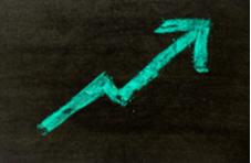 green chalk arrow going upwards on a black chalkboard