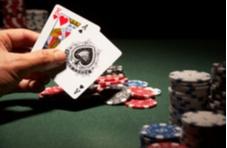 man's hand holding a blackjack hand and piles of chips