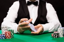 the hands of a blackjack dealer shuffling cards with chips on the table