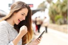 happy young woman because she just won at Springbok casino playing video poker on her phone 