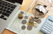 photo of laptop, bank statement, calculator and coins spilling out of a jar all indicating online money management