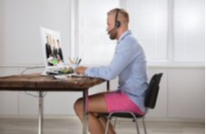 man working from a desk at home in a shirt and shorts