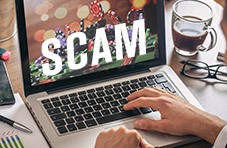 A laptop screen with the word SCAM stamped across the image